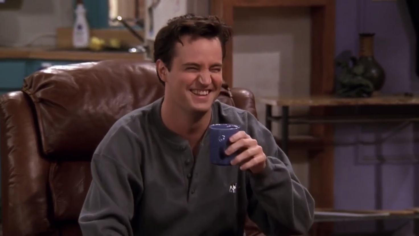 Chandler Bing rindo com uma caneca no apartamento de Monica em Friends